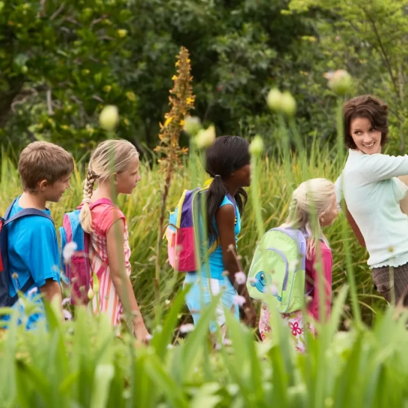 A group of children follow their teacher outside.