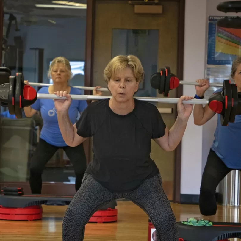 Woman in group exercise class lifting weights