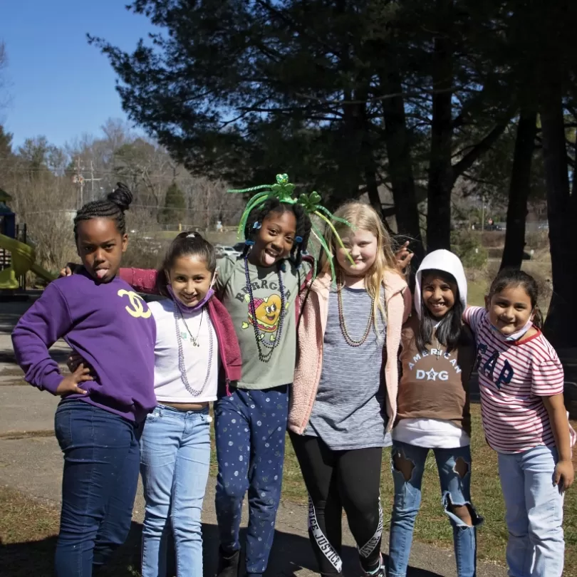 Afterschool group of girls posing arms around each other with silly faces