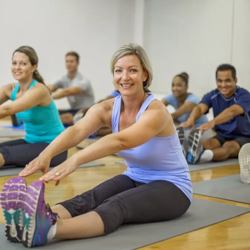 People on yoga mat stretching in group exercise class with 