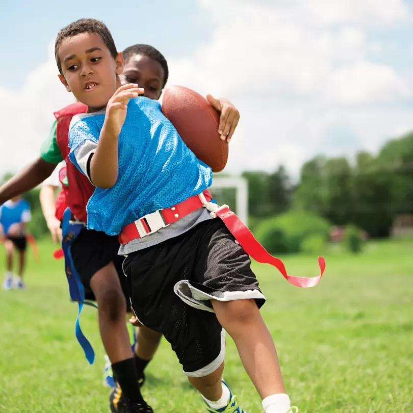 Flag football players run down the field with the ball