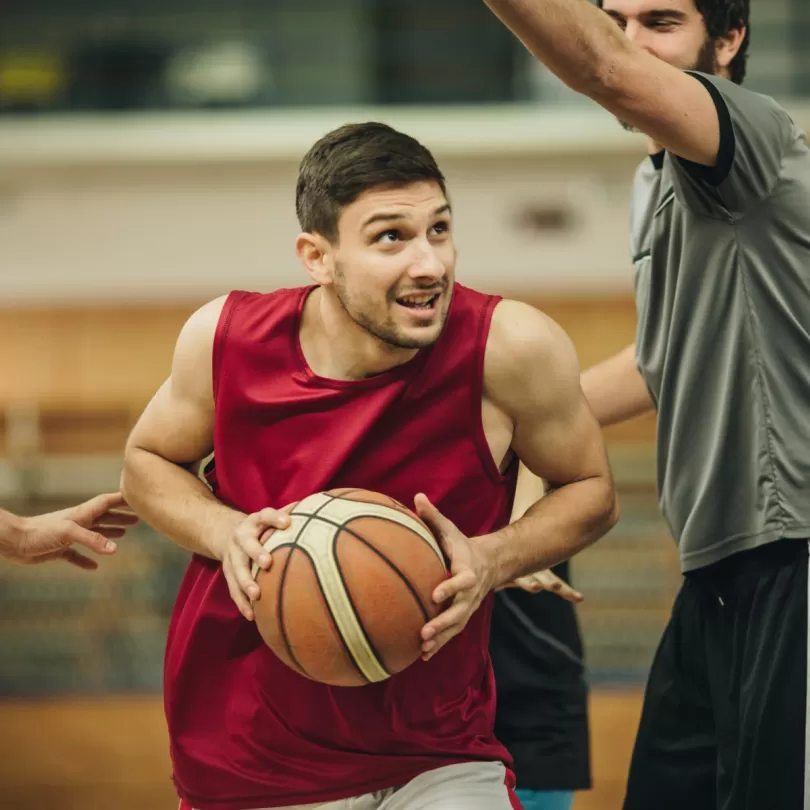 basketball game, man going in for a basket trying to avoid the defender who is trying to block the ball