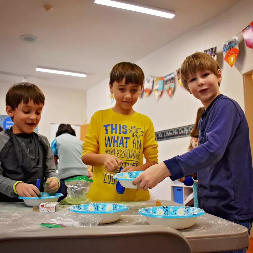 Three boys making gak in a school setting 