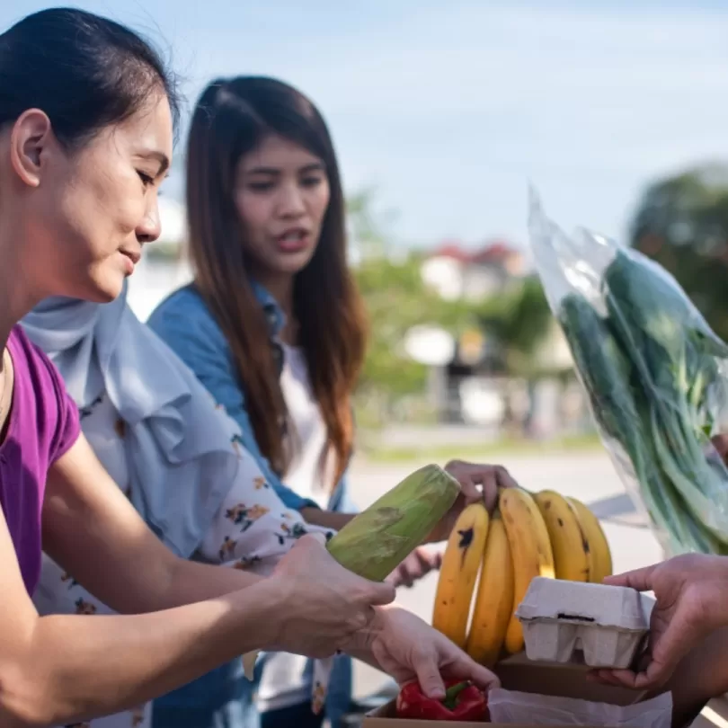 A group of people volunteer at a food drive and place food into boxes.
