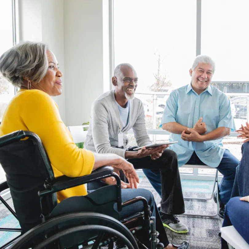 A group of older adults sit and discuss during a support group.