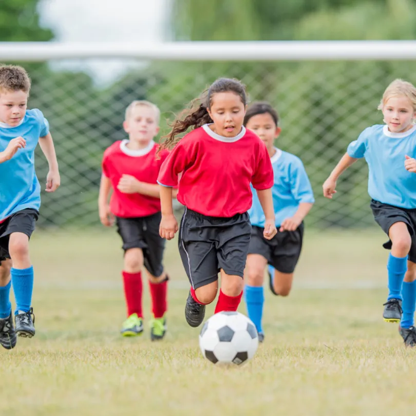 Two youth soccer teams play a game on an outdoor field.