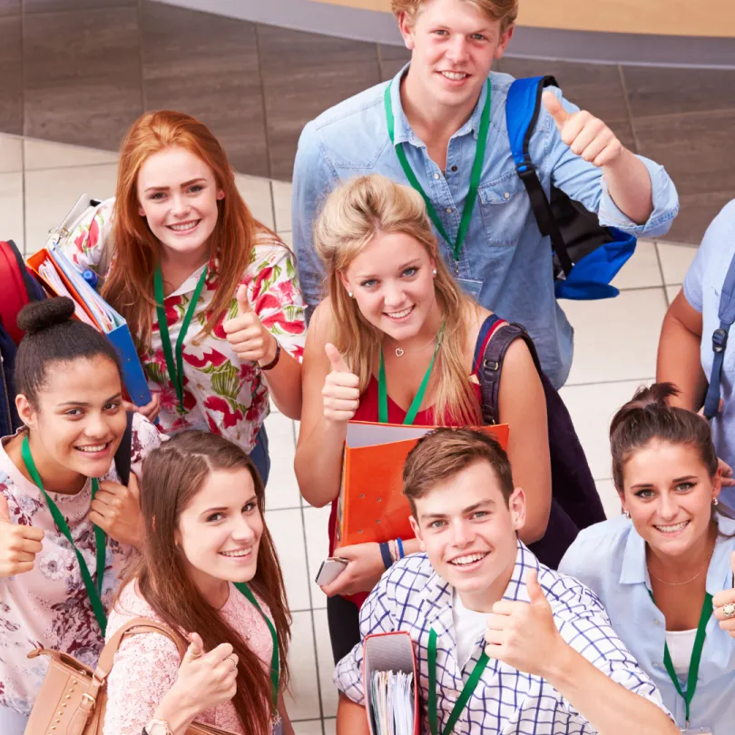 A group of students smile at the camera with thumbs up.