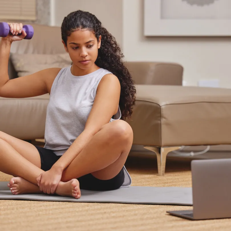 A woman works out with weights at home usually virtual classes on YMCA360.