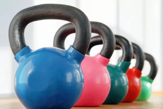 A row of different colored kettlebells sitting on the floor.