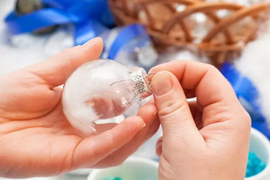 A closeup of a pair of hands making a Christmas ornament.