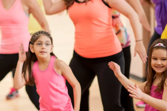 A group class of all ages doing Zumba.