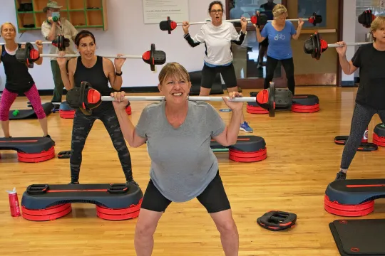 People smile as they exercise in a Les Mills group exercise class.