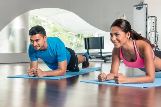 Two people participate in a calisthenics group exercise class.