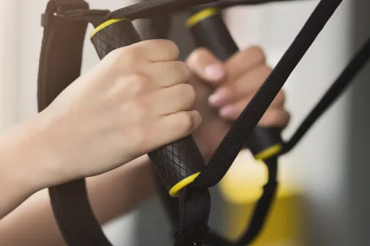 A close up of hands using TRX equipment during a group exercise class.
