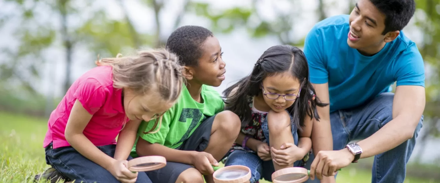 Camp counselor with young children in grass