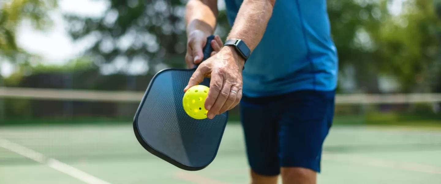 Adult playing pickleball on an outside court.