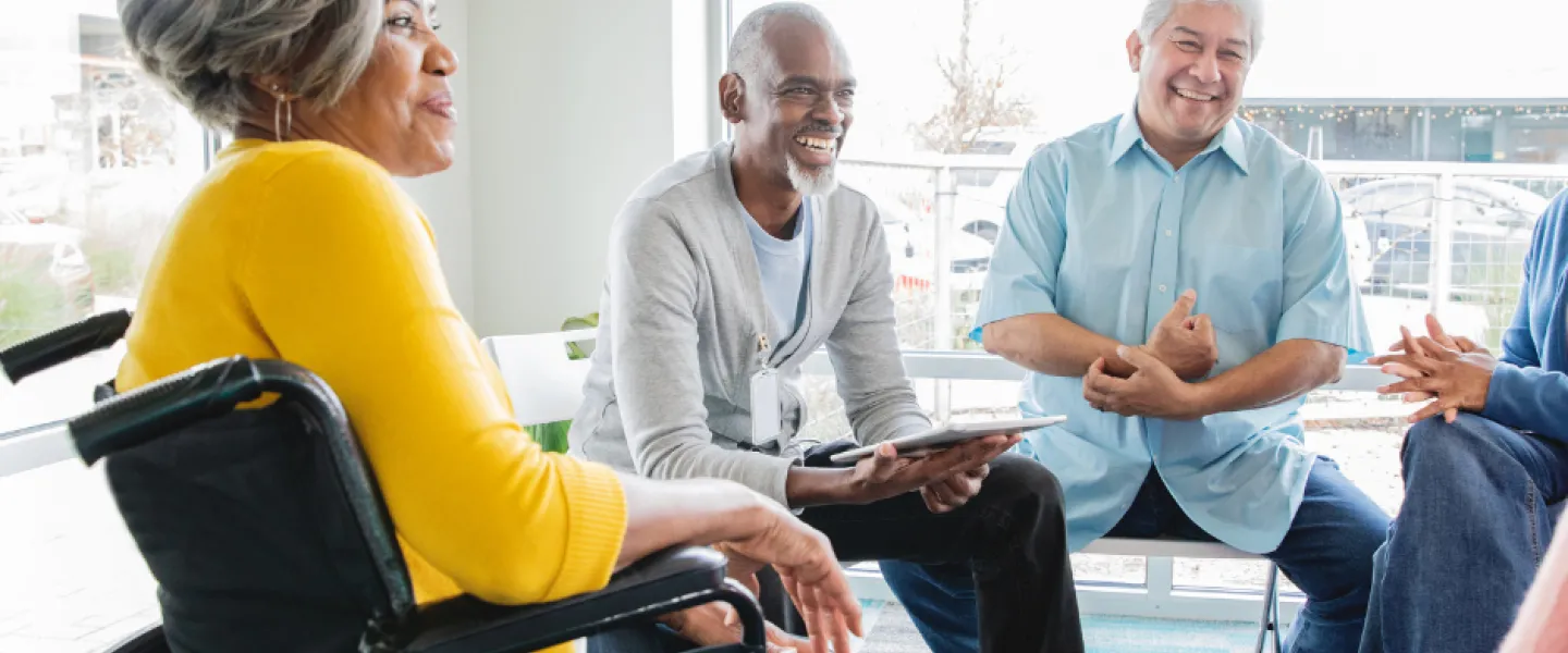 A group of older adults sit and discuss during a support group.