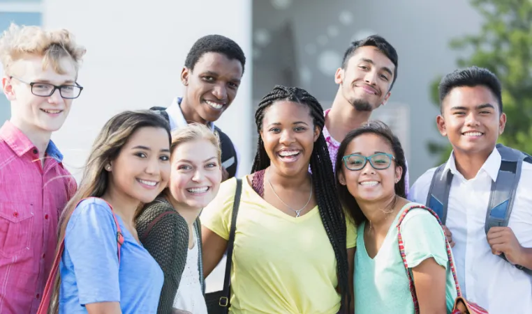 A group of teens smile at the camera at school.