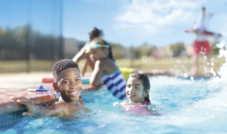 A boy smiles in a swimming pool.