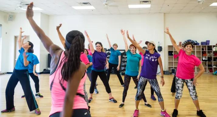 An instructor leads a dance group exercise class at the gym.