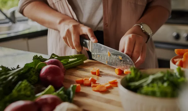 A person cuts vegetables in their kitchen,