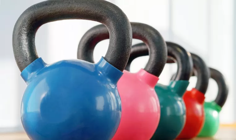 A row of different colored kettlebells sitting on the floor.