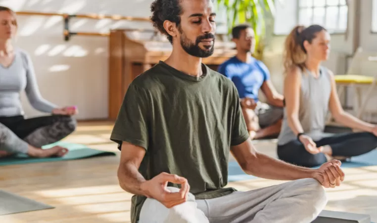 A man meditates on the floor in class.