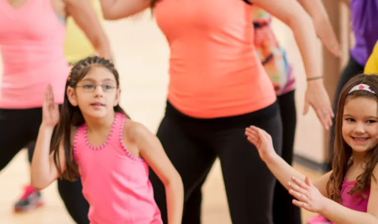 A group class of all ages doing Zumba.