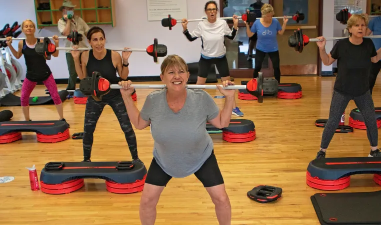 People smile as they exercise in a Les Mills group exercise class.