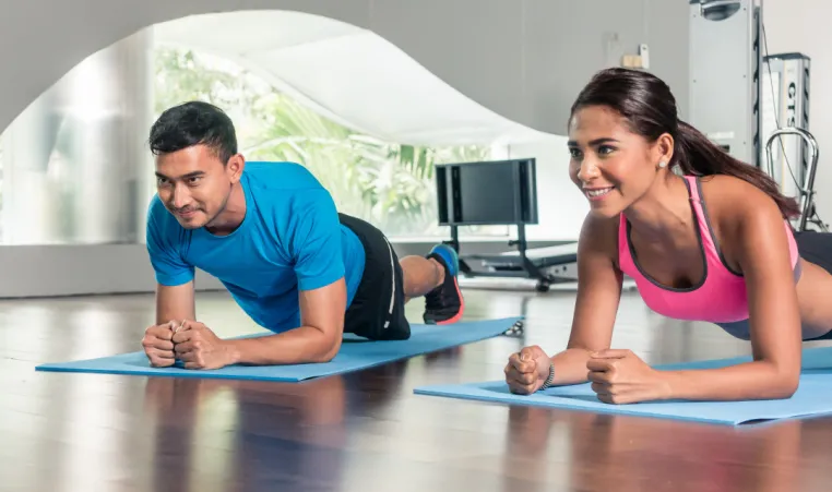 Two people participate in a calisthenics group exercise class.