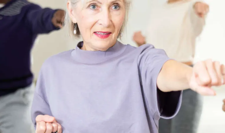 An older woman learns self defense in a group class.